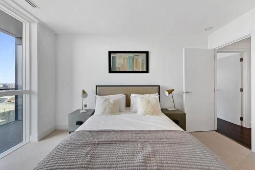 a white bedroom with a large bed and a window at Large Canary Wharf 2 Bed Apartment with High Rise view in London