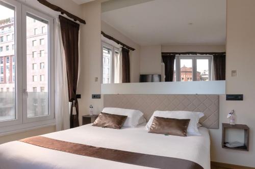 a bedroom with a large white bed with windows at Aiello Rooms - San Babila in Milan