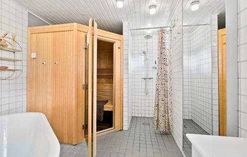 La salle de bains est pourvue d'une douche et d'une armoire en bois. dans l'établissement Beautiful Home In Aakirkeby With Wifi, à Åkirkeby