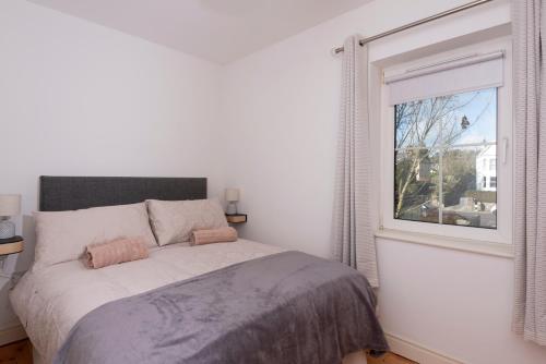 a white bedroom with a bed and a window at 5 Bruach na hAbhann in Clonakilty