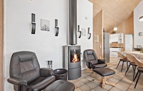 a living room with leather chairs and a fireplace at Awesome Home In Nørre Nebel With Sauna in Nørre Nebel
