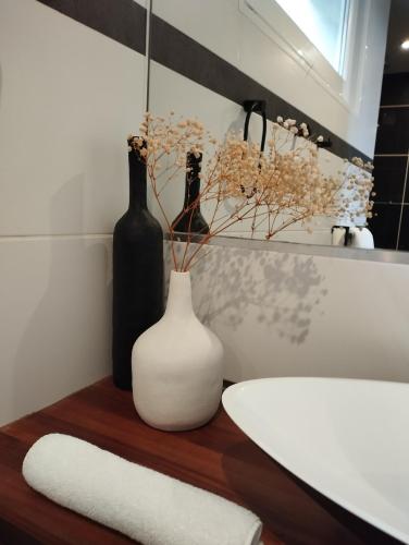 a bathroom with two bottles and a white vase on a wooden table at Au coucher du lac in Publier