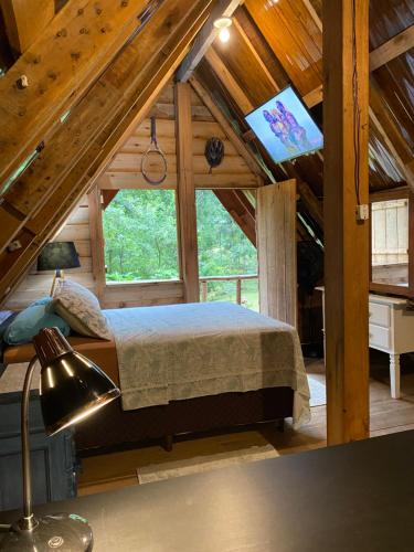 a bedroom in a log cabin with a bed and a tv at Chalé em meio à natureza! in Guabiruba