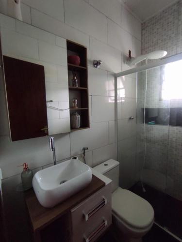 a bathroom with a toilet and a sink and a shower at Casa 2 qtos, sendo suíte com cama Queen ar condicionado in Guapimirim