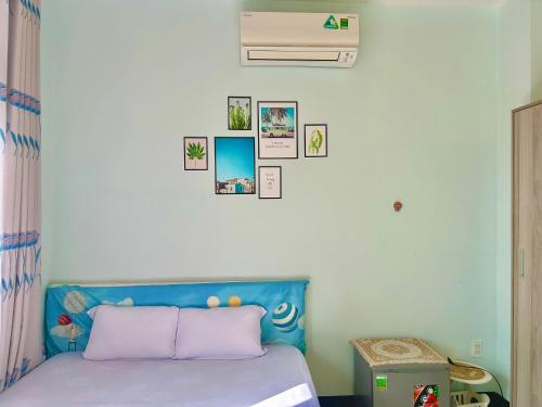 a bedroom with a blue bed with pictures on the wall at Lộc Vừng Homestay in Phan Thiet