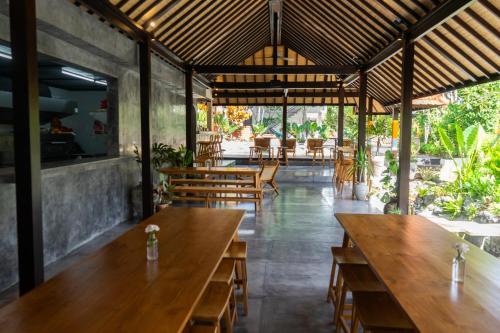 un restaurante con mesas de madera y sillas de madera en Savanna Ubud, en Ubud