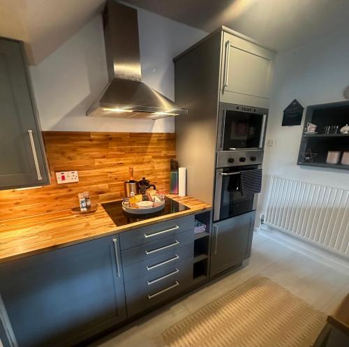 a kitchen with stainless steel appliances and wooden counters at Airthrey Cottage in Bridge of Allan