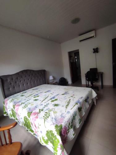 a bedroom with a bed with a flowered blanket on it at Casa 2 qtos, sendo suíte com cama Queen ar condicionado in Guapimirim