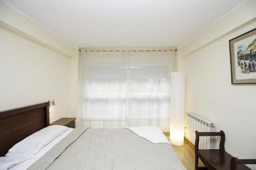 a white bedroom with a bed and a window at Apartamento céntrico en Girona in Girona