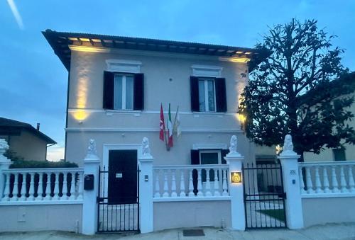 a large white house with a white fence at FOUR LIONS VILLA GUESTHOUSE in Pisa