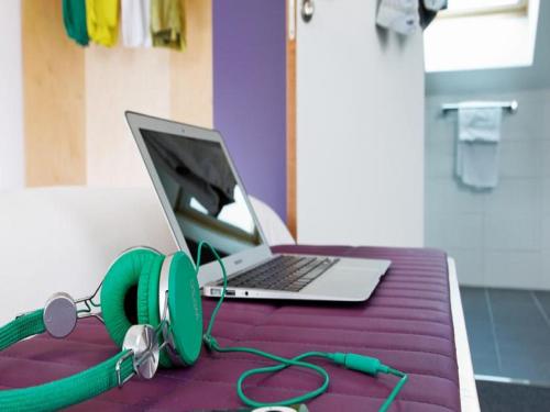 a laptop computer sitting on a purple table with headphones at ibis Styles Calais Centre in Calais