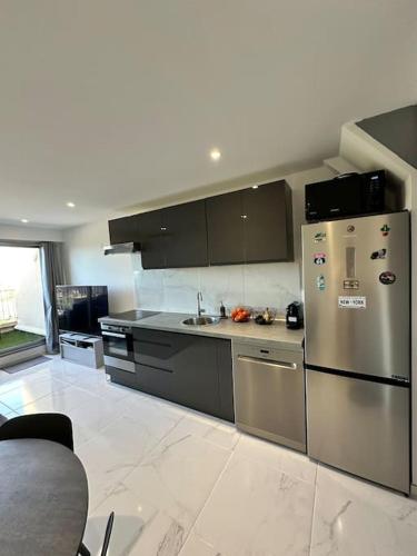 une cuisine avec un réfrigérateur en acier inoxydable et un évier dans l'établissement T2 Duplex climatisé et rénové avec terrasses - Hyères Port, à Hyères