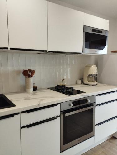 a kitchen with white cabinets and a stove top oven at Au coucher du lac in Publier