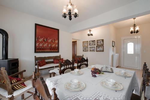 a dining room with a white table and chairs at Prasini Folia - Traditional Residence in Anogia
