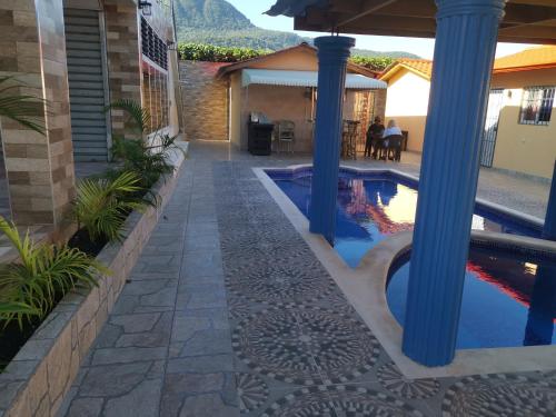 a swimming pool with blue columns and a house at Villa Bellevue in San Felipe de Puerto Plata