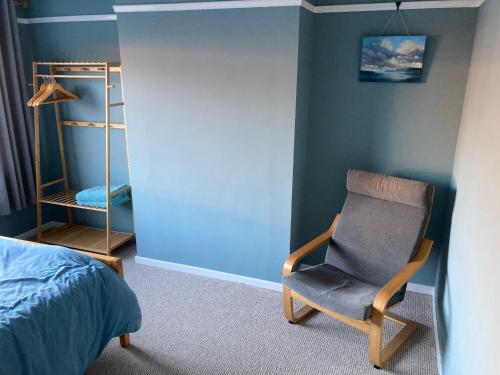 ein Schlafzimmer mit einem Stuhl neben einem Bett in der Unterkunft Cosy at Cumberland - Double room with shared bathroom in Dundonald