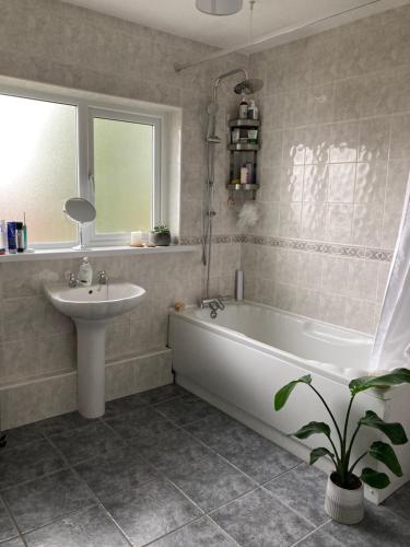 a bathroom with a sink and a bath tub and a sink at Cosy at Cumberland - Double room with shared bathroom in Dundonald