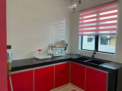 uma cozinha com armários vermelhos, um lavatório e uma janela em D Sayang Homestay Parit Buntar MUSLIM SAHAJA em Parit Buntar
