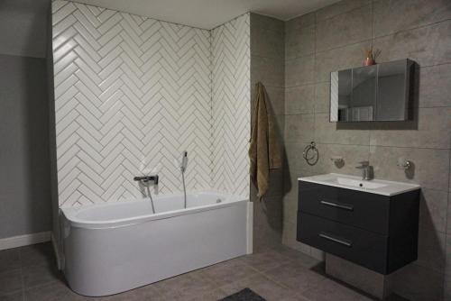 a bathroom with a bath tub and a sink at Airfield Manor in Castle Donington