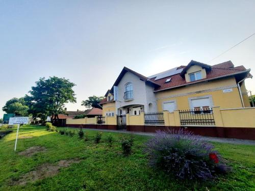 una casa gialla con una recinzione in un cortile di Sóvirág Termál Panzió a Hajdúnánás