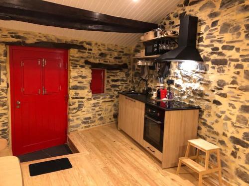 cocina con puerta roja y pared de piedra en Casa dos Veados, 