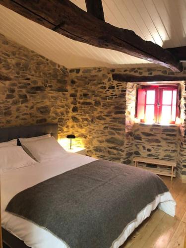 a bedroom with a bed and a stone wall at Casa dos Veados in Ladeiras