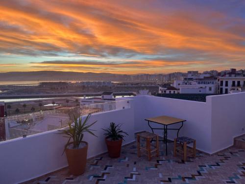einen Balkon mit einem Tisch und Stühlen bei Sonnenuntergang in der Unterkunft Socco Hostel in Tangier