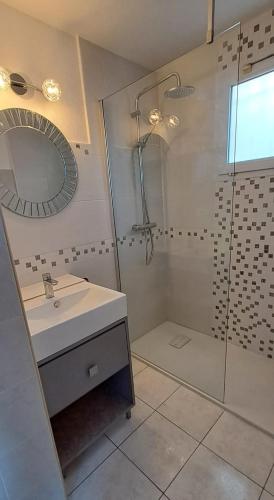 une salle de bain avec une douche, un lavabo et un miroir dans l'établissement La maison coquillage, au Barcarès