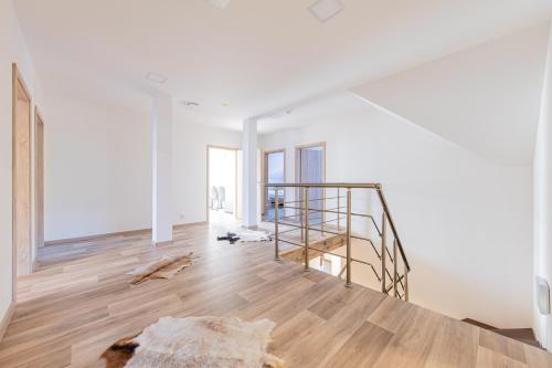 a white room with a wooden floor and a staircase at Chalupa KARKULKA in Hostice