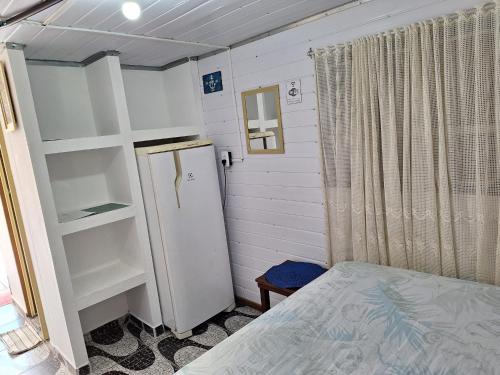 1 dormitorio con 1 cama y nevera. en Recanto do Estaleiro, en Ubatuba