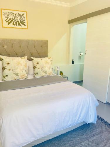 a bedroom with a large white bed with pillows at Private Room Pelican in Durban