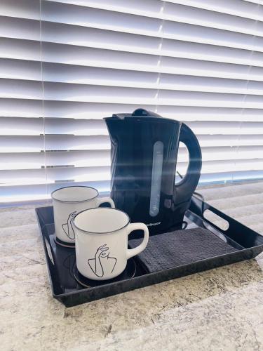 uma bandeja com duas chávenas de café e uma panela sobre ela em Private Room Pelican em Durban