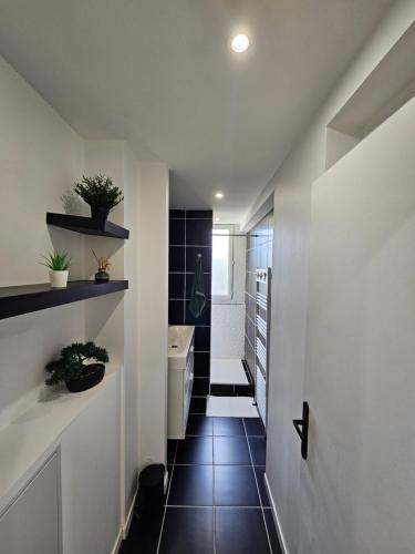 bagno con pavimento piastrellato nero e pareti bianche. di Charmant & spacieux 3 chambres - MM Apartment - Lyon Grand Parilly a Vénissieux