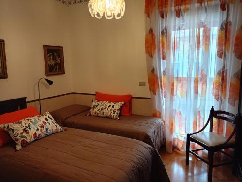 a bedroom with two beds and a chandelier and a window at CASA PERLA in Monfalcone