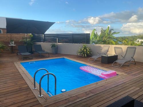 a swimming pool on a deck with chairs and an umbrella at Villa des Grenadelles in Saint-Paul
