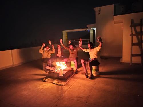 a group of people sitting around a fire at Skylight Residency Yercaud in Yercaud