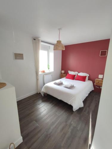 une chambre avec un lit blanc avec des murs rouges dans l'établissement L'ilot des abers Maison de vacances, à Lannilis
