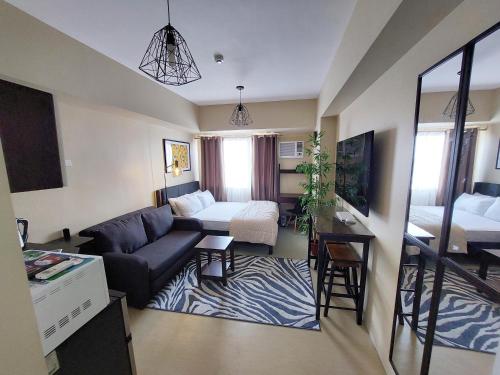 uma sala de estar com um sofá e uma cama em Cozy Studio Unit, Avida Towers Aspira em Cagayan de Oro