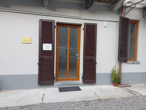 a white building with brown shutters and a door at Iori's House in Mergozzo