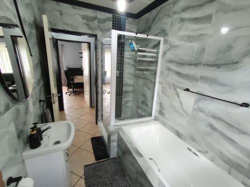 a bathroom with a white tub and a sink at Maneli 69 in Boksburg