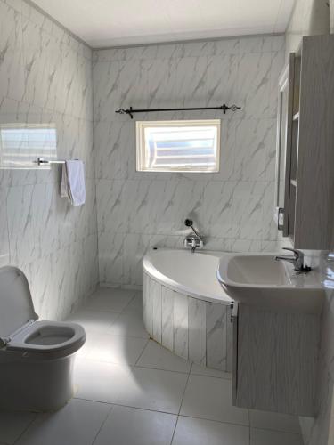 La salle de bains est pourvue d'une baignoire, de toilettes et d'un lavabo. dans l'établissement Swiss Luxury Apartments, à Ndola