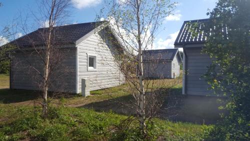 un petit bâtiment blanc à côté d'une maison dans l'établissement Camp-Classic, à Smołdziński Las