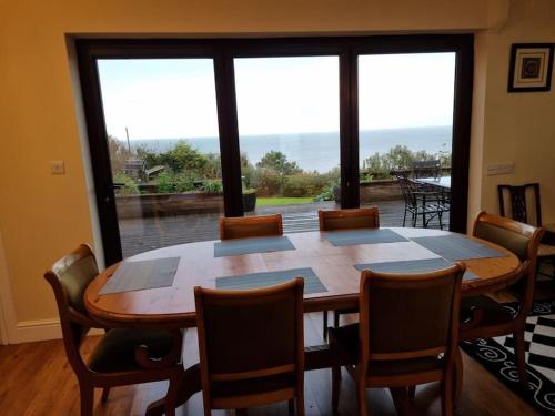 uma mesa de jantar com cadeiras e uma grande janela em Spacious Detached Home with Beautiful Seaviews, sleeps 6 em Trimingham