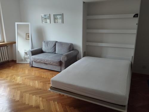 a bedroom with a bed and a couch and a chair at Apartament Parkowy in Bielsko-Biała