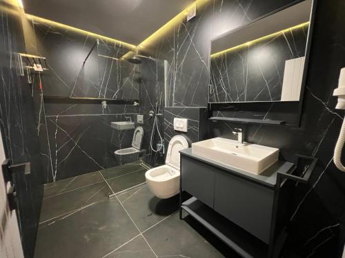 a black bathroom with a toilet and a sink at Apartament Koha 