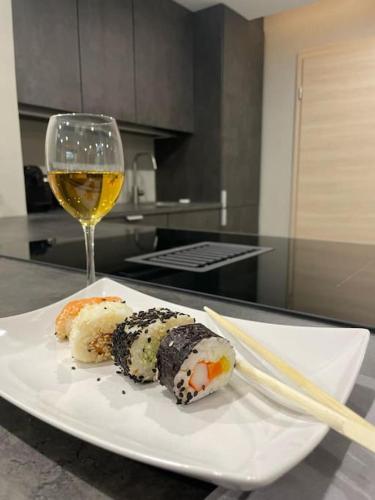 a white plate with sushi and a glass of wine at Moderne Ferienwohnung in Waldrandlage mit einem Hauch von Luxus in Burgthann