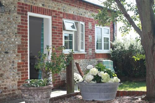 een bakstenen huis met twee potplanten ervoor bij The Hen House in Chichester