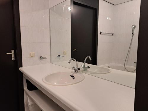 een witte badkamer met een wastafel en een douche bij Zuiderzeestate 35, prachtig appartement aan het IJsselmeer in Makkum