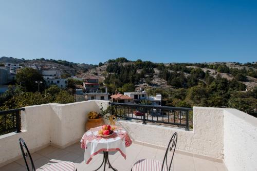 a table and chairs on a balcony with a view at Prasini Folia - Traditional Residence in Anogia