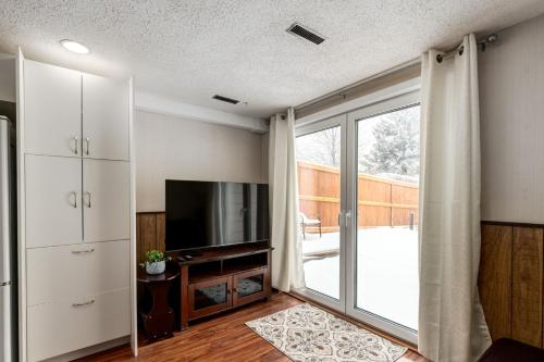 a living room with a television and a sliding glass door at Cozy 2BR Walkout Suite Near YYC Free Parking in Calgary